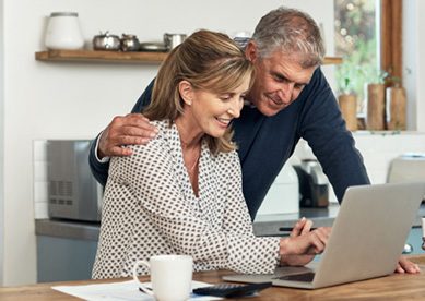Senior couple looking at laptop at kitchen table